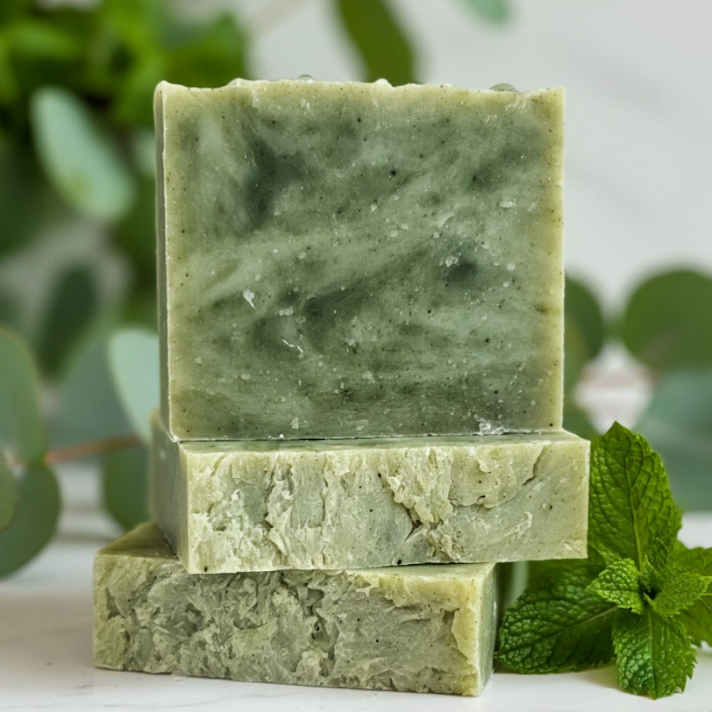 Handcrafted soap bar with soothing shades of mint green, white, and soft teal swirls, inspired by the invigorating blend of eucalyptus and spearmint. Refreshing, crisp, and calming.